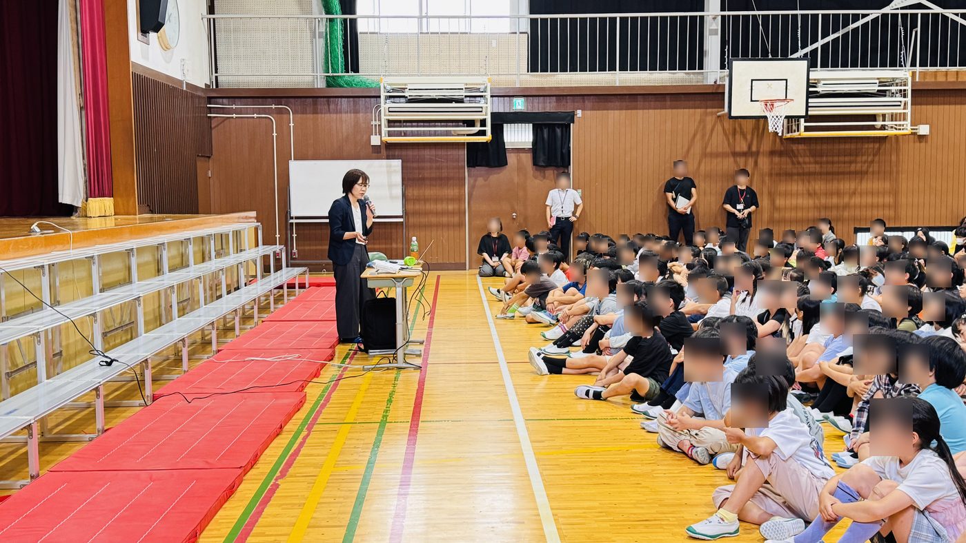 演台に立つ講師と、座って聞く児童たち