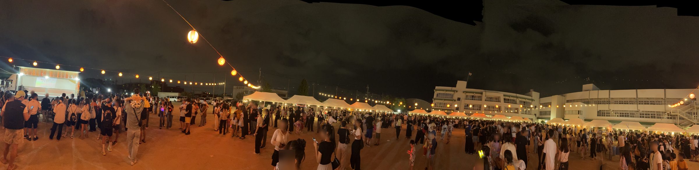 提灯の明かりが連なる夜の会場全体のパノラマ写真